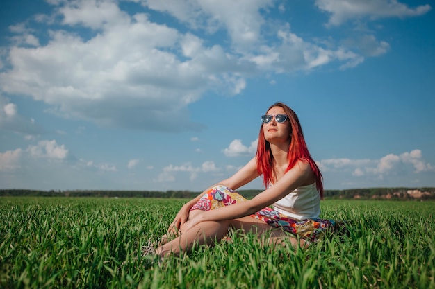 Ragazza seduta in un campo sul cielo blu di erba verde Copia spazio