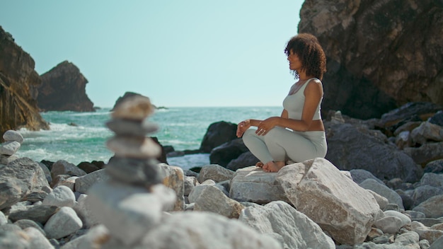 Ragazza seduta rilassante posa del loto sulla spiaggia di pietra Ursa Donna meditando sulla natura