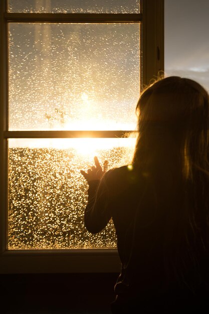 ragazza seduta su un davanzale e guardando la città di sera