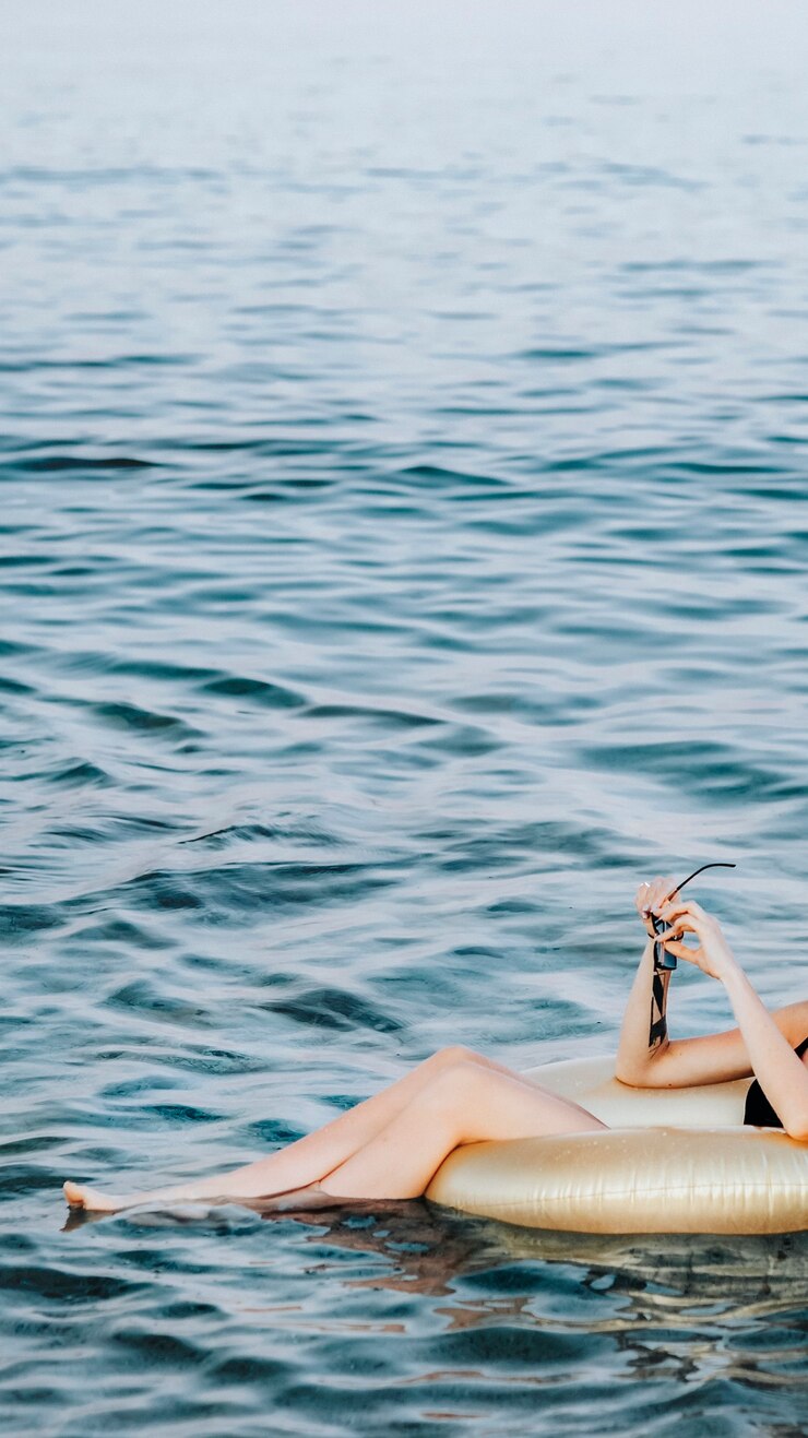 Foto ragazza seduta su un tubo da bagno d'oro nell'oceano sfondo del telefono cellulare