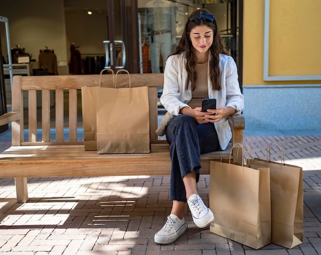 Ragazza seduta su una panchina guardando il suo telefono cellulare Riposo durante lo shopping in un centro commerciale