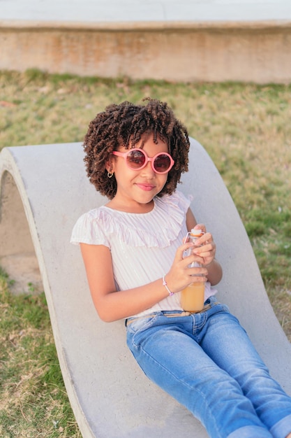 Ragazza seduta su una panchina nel parco a bere succo