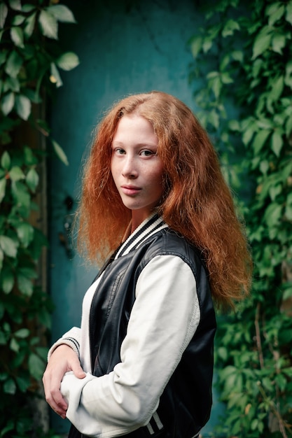 Ragazza sensuale con i capelli rossi sul muro verde in abito casual