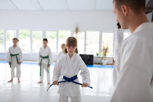 Ragazza seria. Bambina sveglia che indossa l'aikido bianco con una faccia seria prima di praticare l'aikido