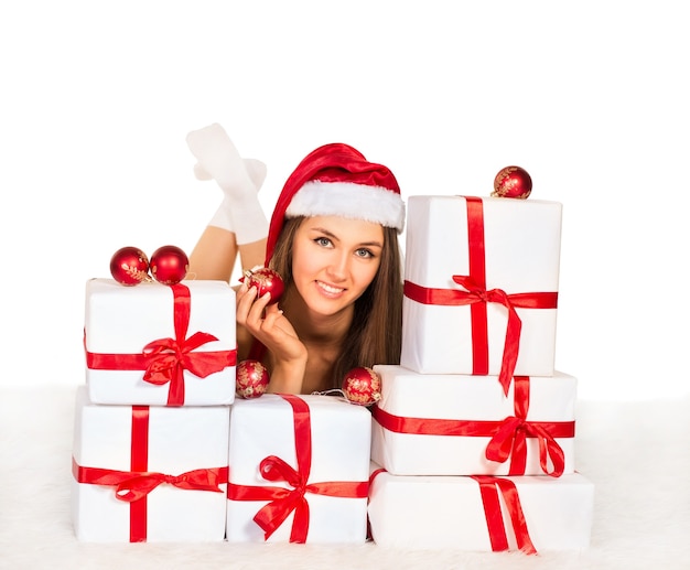 Ragazza sexy con regali di Natale sdraiato sul tappeto, sorridente e guardando la telecamera