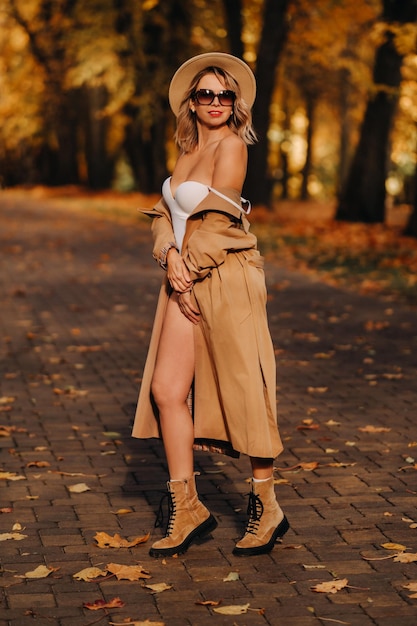 Ragazza sexy in un cappotto e un cappello in un parco soleggiato di autunno