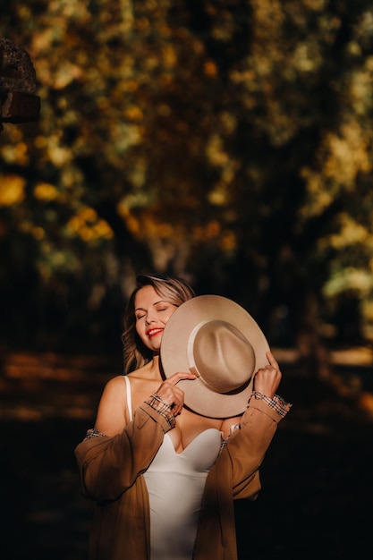 Ragazza sexy in un cappotto e un cappello in un parco soleggiato di autunno