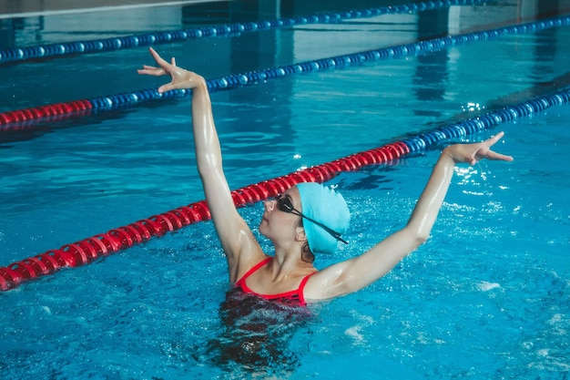 Ragazza sincronizzata che fa acrobazie in piscina Sport di nuoto sincronizzato in acqua Sportiva professionista che fa esercizi in piscina Allenamento prima della competizione