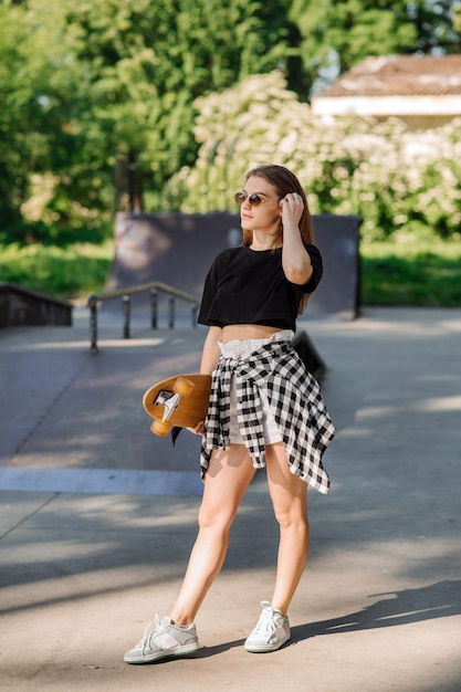 Ragazza skater adolescente con uno skateboard sul parco dei pattinatori