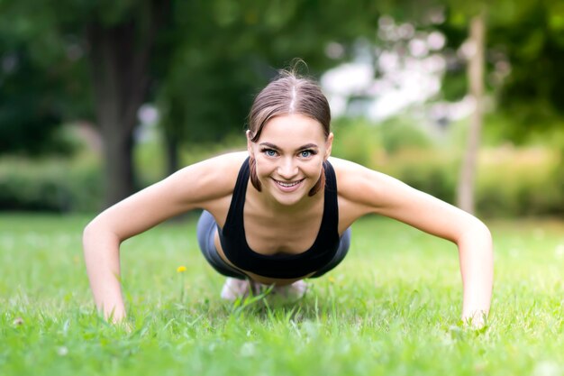 Ragazza snella in forma sportiva in una buona forma, giovane bella donna felice che fa esercizio, push up