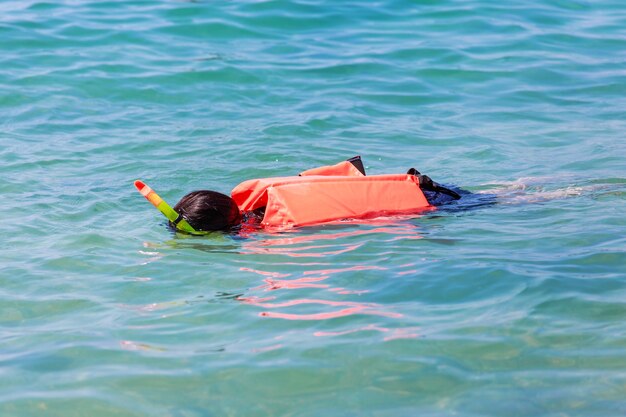 ragazza snorkeling nuotare in giacca di vita con maschera e tubo di respirazione