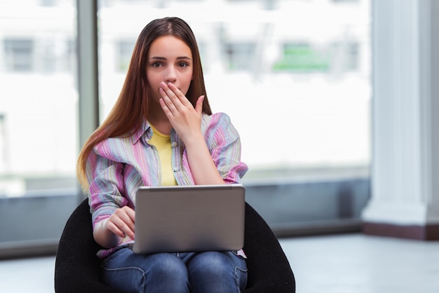 Ragazza sonnolenta che lavora al computer portatile