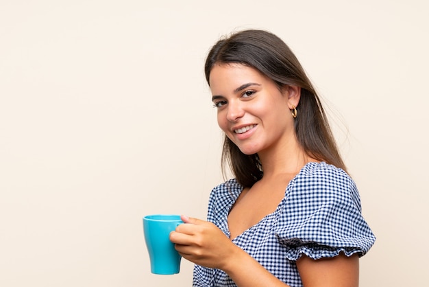 Ragazza sopra la parete isolata che tiene tazza di caffè calda