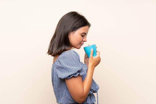 Ragazza sopra la parete isolata che tiene tazza di caffè calda