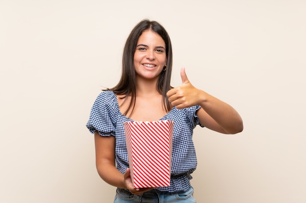 Ragazza sopra la parete isolata che tiene una ciotola di popcorn