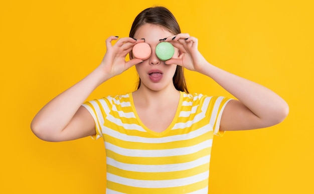 Ragazza sorpresa con macaron su sfondo giallo