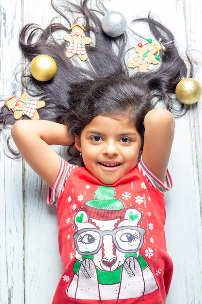 Ragazza sorridente allegra sveglia con i capelli decorati di Natale