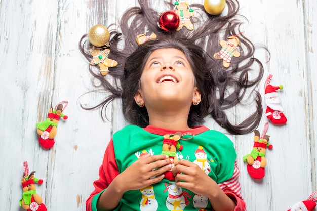 Ragazza sorridente allegra sveglia con i capelli decorati di Natale