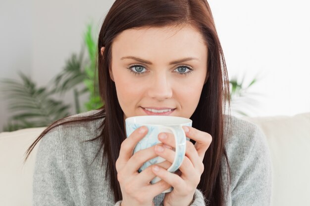 Ragazza sorridente che beve una tazza di caffè