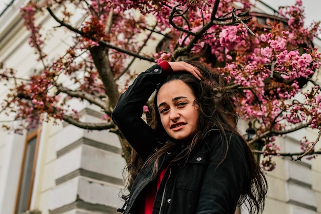 Ragazza sorridente che gode degli alberi primaverili dell'infiorescenza