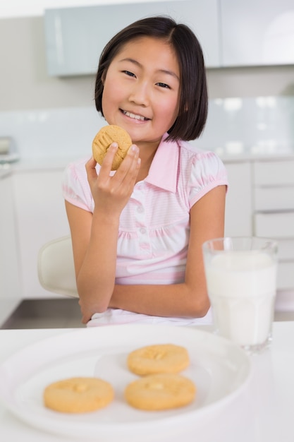 Ragazza sorridente che gode di biscotti e latte