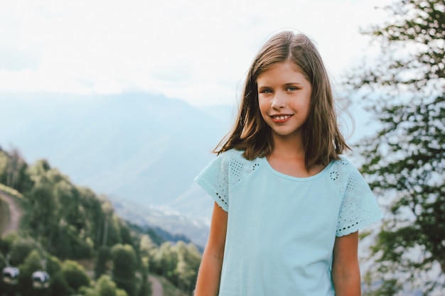 Ragazza sorridente che guarda l'obbiettivo sullo sfondo di bellissime montagne