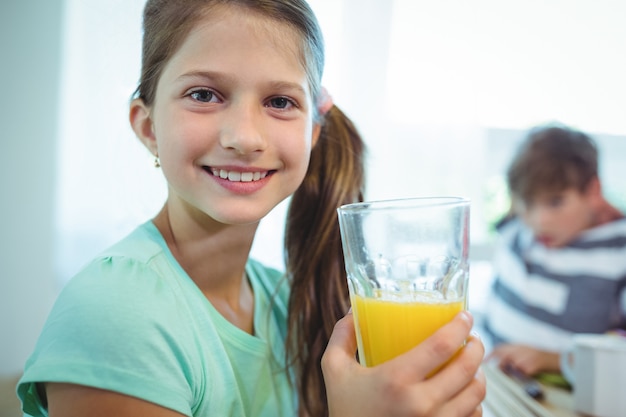 Ragazza sorridente che mangia il succo di arancia