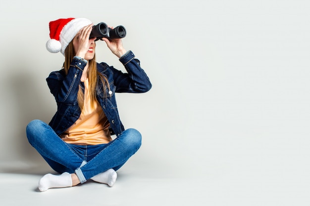 Ragazza sorridente che porta un cappello di Santa Claus su un fondo leggero