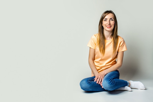 Ragazza sorridente che si siede sul pavimento