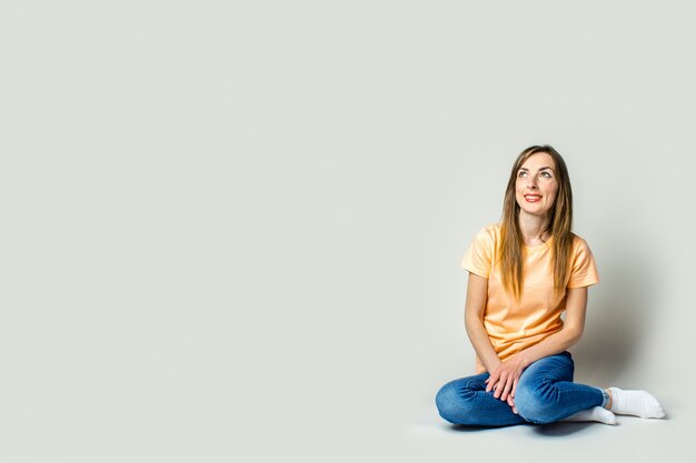 Ragazza sorridente che si siede sul pavimento