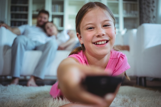 Ragazza sorridente che si trova sulla coperta e che cambia i canali