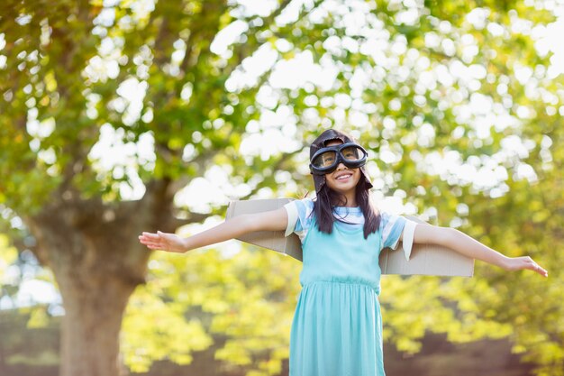 Ragazza sorridente che sta con le armi stese in parco