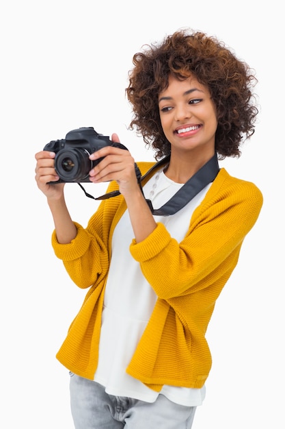 Ragazza sorridente che tiene macchina fotografica digitale e guardarla