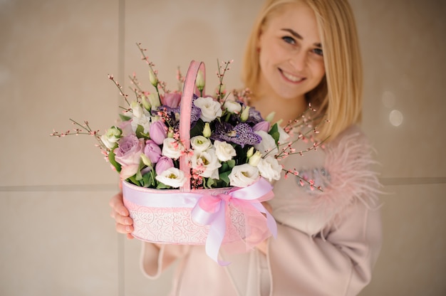 Ragazza sorridente che tiene un cestino della sorgente dei fiori bianchi e viola teneri