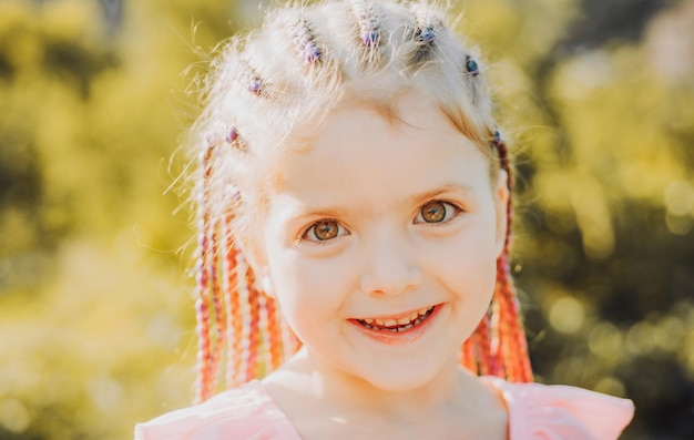 Ragazza sorridente con capelli dreadlocks bambino con capelli alla moda bambino felice all'aperto fuori