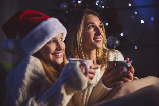 Ragazza sorridente con la madre che aspetta Babbo Natale al chiuso