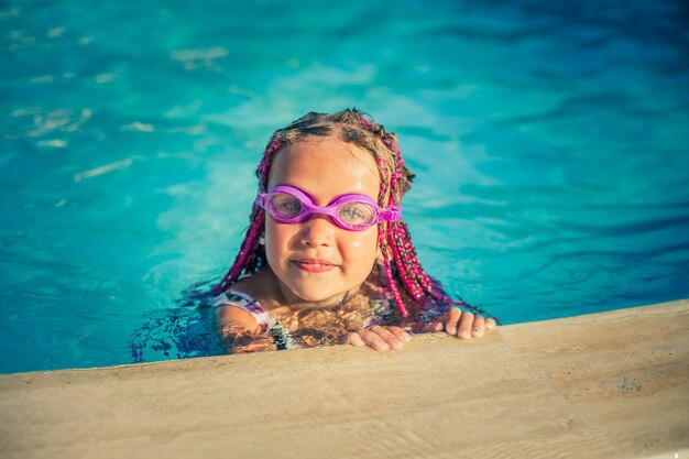 Ragazza sorridente con occhiali rosa per nuotare in piscina