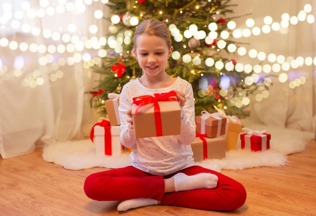 ragazza sorridente con un regalo di Natale a casa