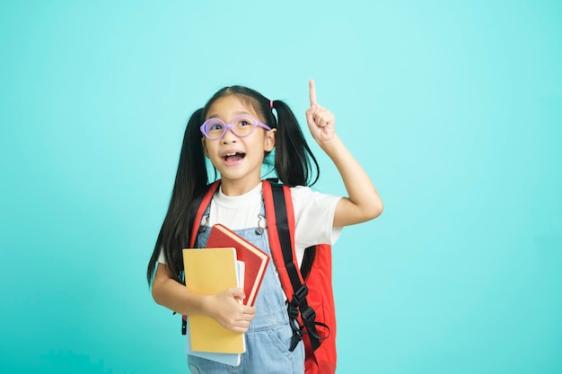 Ragazza sorridente degli studenti del bambino del primo piano che tiene libro che va a scuola