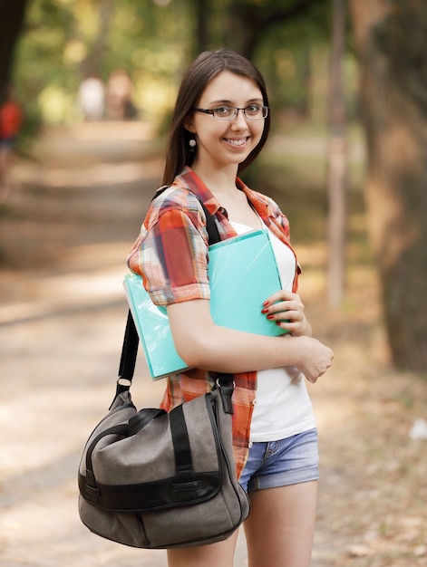 Ragazza sorridente dell'allievo con una lavagna per appunti sui precedenti del parco.