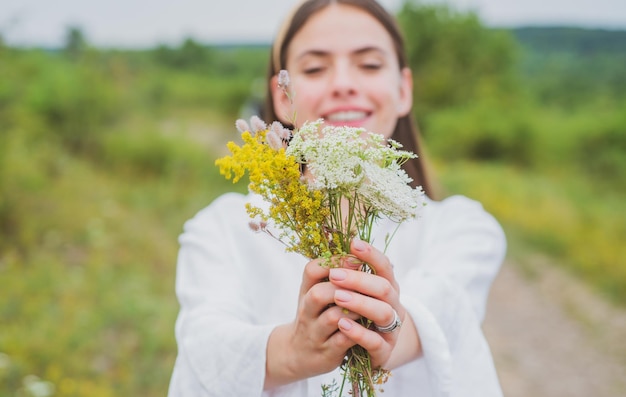 Ragazza sorridente della primavera nel campo donna di stile di vita sano in prato con il campo organico dei fiori selvaggi