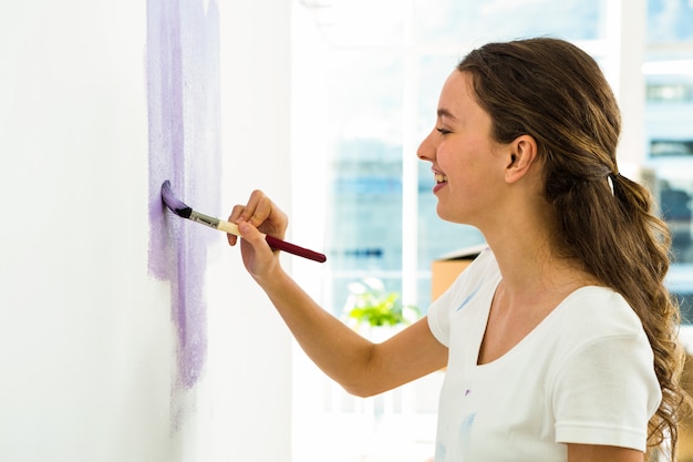 Ragazza sorridente e dipingere un muro