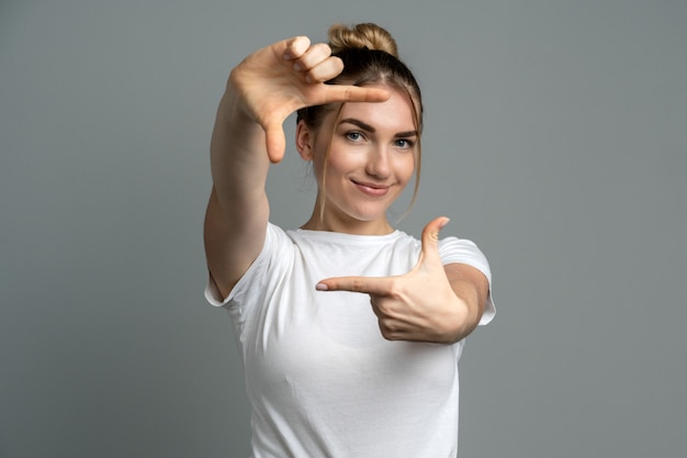 ragazza sorridente e facendo una cornice imitazione con le dita