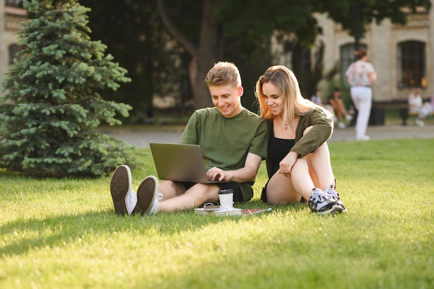 Ragazza sorridente e giovane che studiano con il computer portatile alla pausa del parco Tempo libero degli studenti