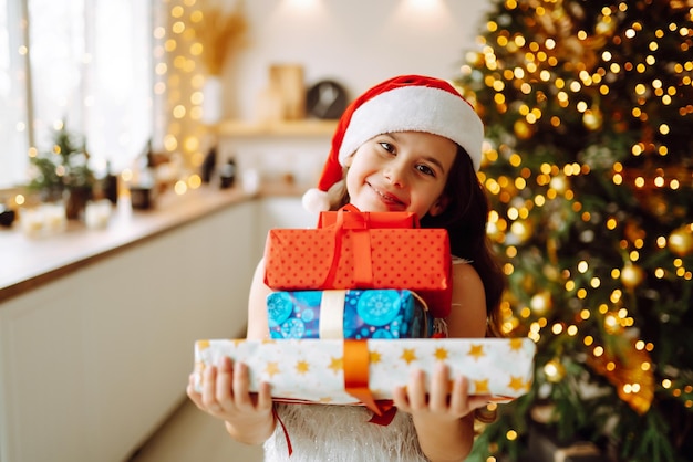 Ragazza sorridente felice con scatole regalo di Natale Cute Child si diverte vicino all'albero