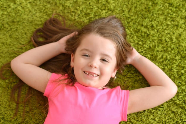 Ragazza sorridente sdraiata sul tappeto