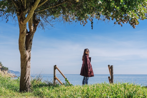 Ragazza sotto un albero sullo sfondo del mare in inverno