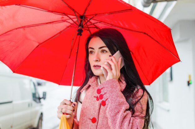 Ragazza sotto un ombrello rosso in città