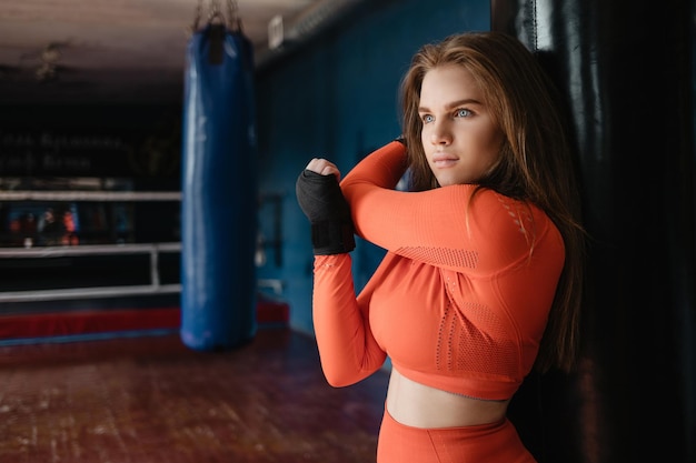 Ragazza sportiva in bende da boxe vicino a un sacco da boxe