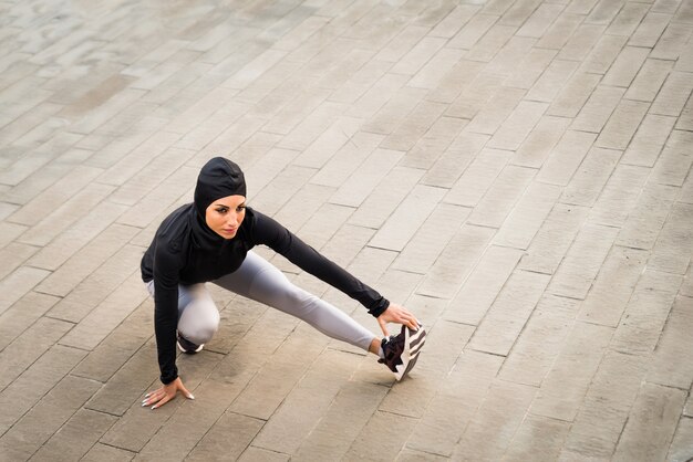 Ragazza sportiva musulmana con allenamento del corpo in forma all'esterno